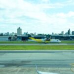 Avião ATR 72 da Voepass, amarelo e branco, em uma pista de aeroporto, com prédios da cidade ao fundo