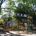 Entrada do Parque Mutirama, em Goiânia, com o arco com o nome do parque e dois bonecos de palhaço, cercada de árvores