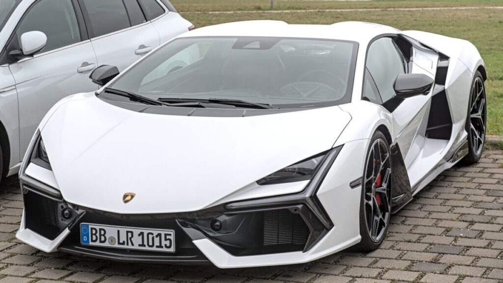 Lamborghini Revuelto branca estacionada, vista de frente e de lado, ao lado de outro carro