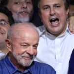 Lula sorri ao centro de um grupo de aliados que comemoram e cantam, em meio à festa da vitória