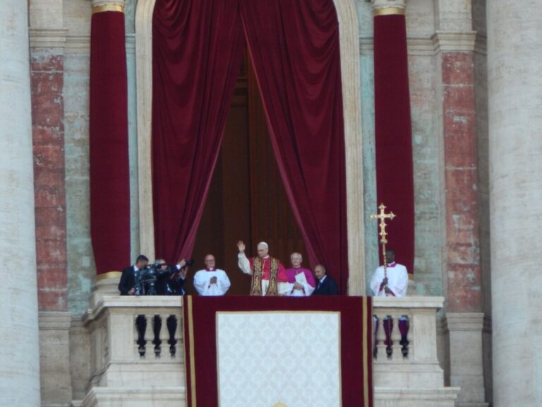 O papa Leão XIV acena da sacada da Basílica de São Pedro, ao lado de outros religiosos, em sua primeira aparição como papa