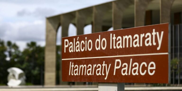 Placa marrom com os dizeres Palácio do Itamaraty e Itamaraty Palace, diante das arcadas do edifício