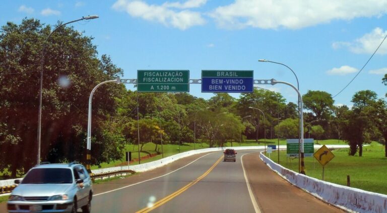 Pista de acesso a uma ponte internacional, com placas sobre a pista indicando Brasil, bem-vindo e fiscalização a 1.200 metros