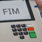 Urna eletrônica exibindo a tela com a palavra FIM, ao lado do teclado com os botões branco, corrige e confirma