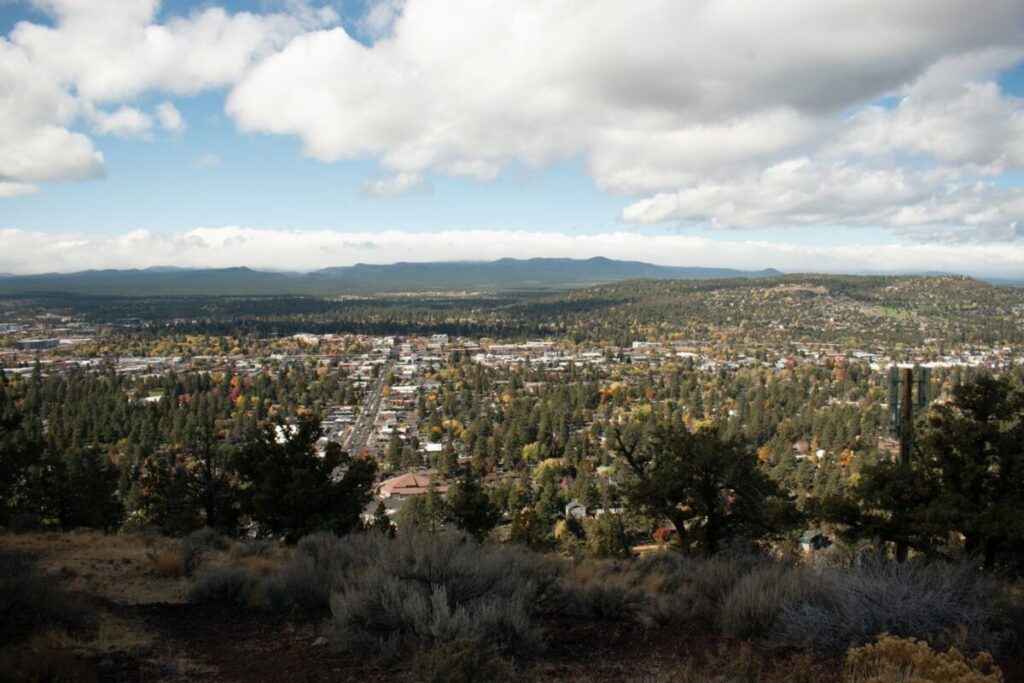 Vista da cidade de Bend, no Oregon, a partir de uma colina, com casas, árvores e montanhas ao fundo